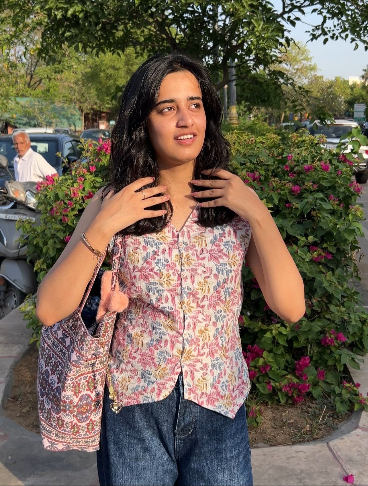 Woman wearing Wild Garden sleeveless cotton top with floral block print and button-down front, paired with blue jeans