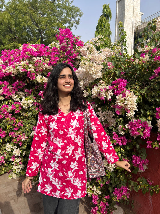 Woman wearing pink floral cotton short kurta in front of pink and white bougainvillea