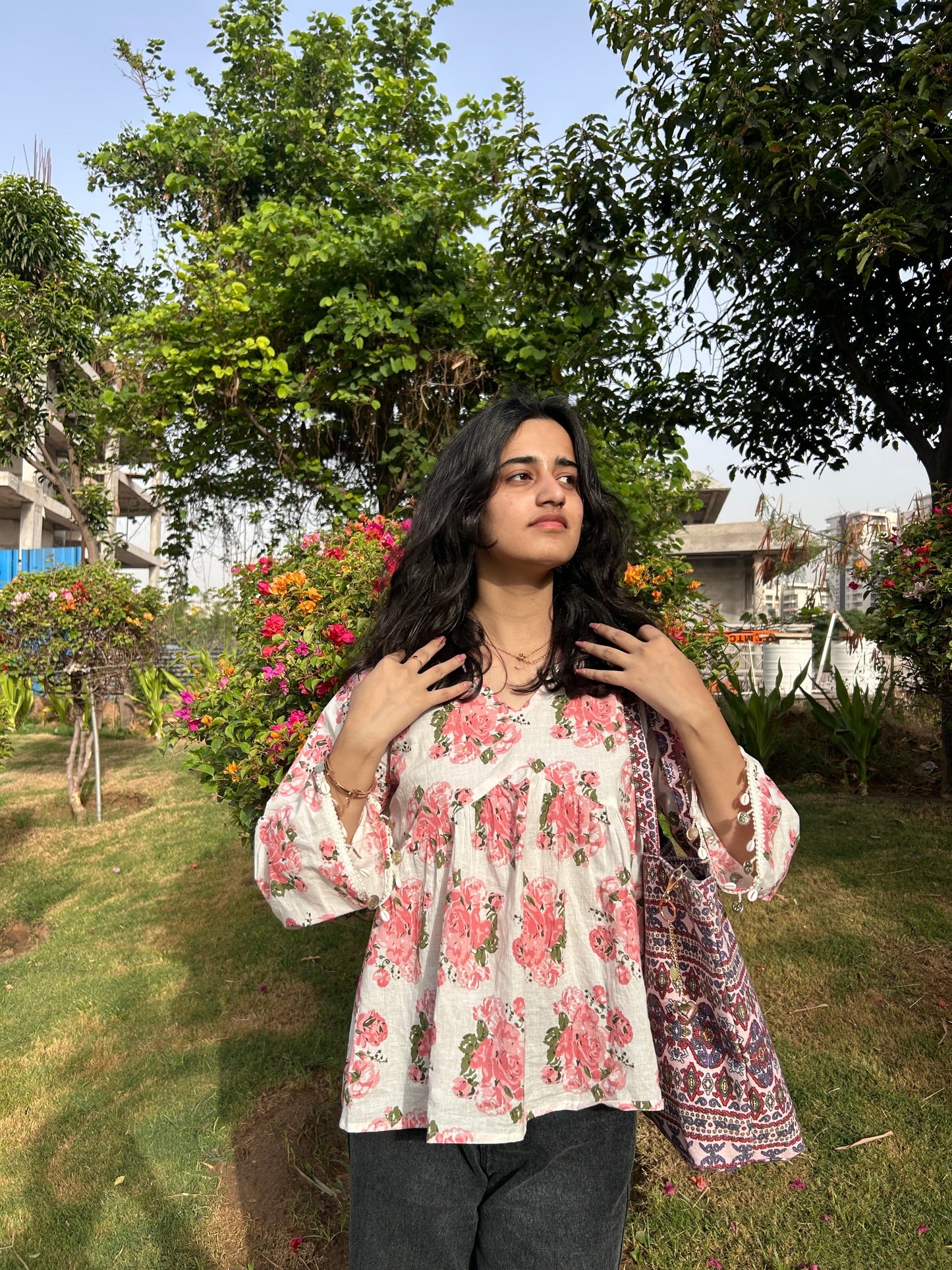 Woman wearing blush pink floral short cotton kurti with bell sleeves in a garden